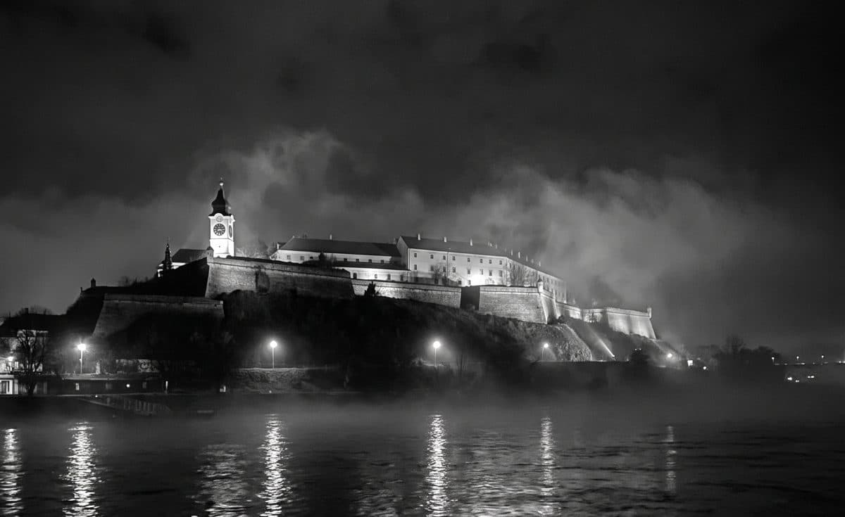 Dunav noću, preko vode osvetljene zidine Tvrđave sa sahat-kulom, magla nad rekom