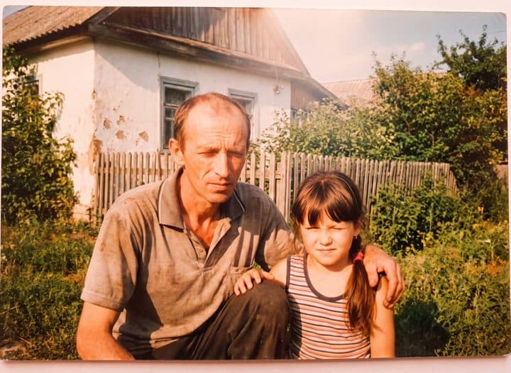 Stara porodična fotografija: otac čuči pored devojčice ispred kuće